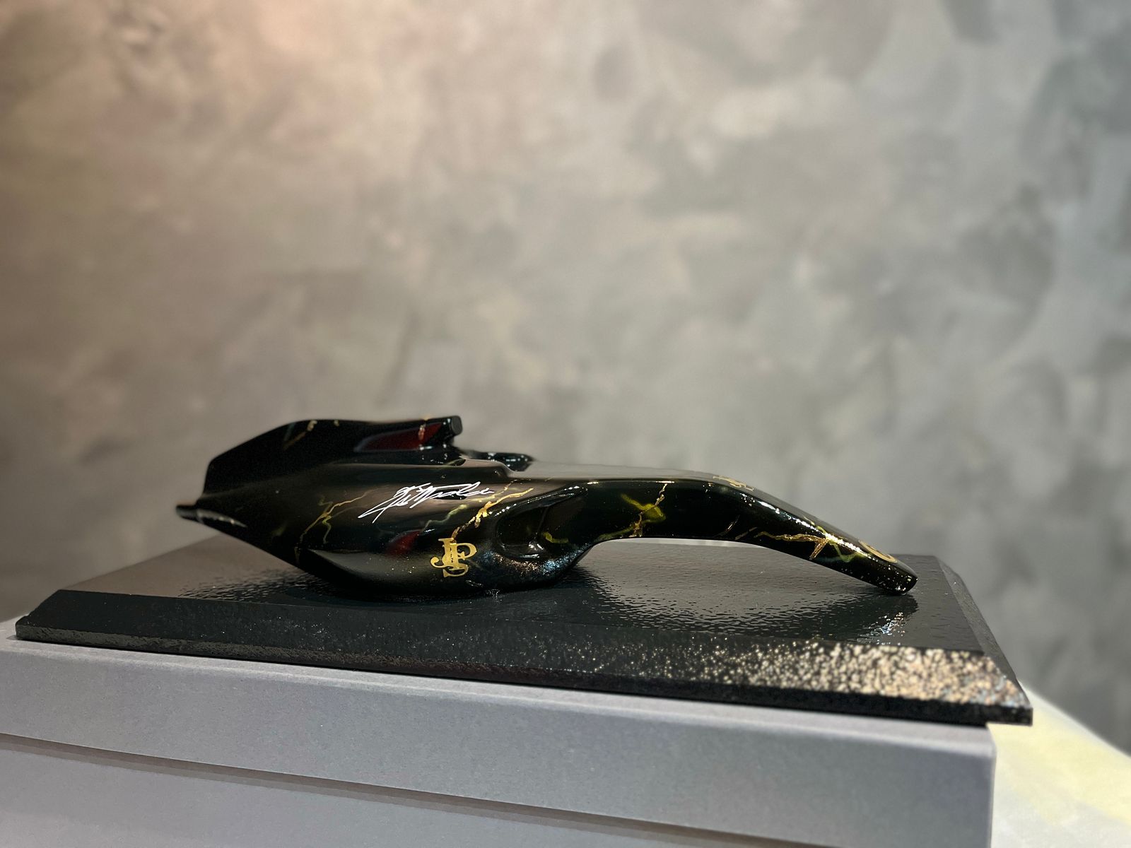 Escultura de mesa preta com detalhes dourados da coleção AMK Emerson Fittipaldi.